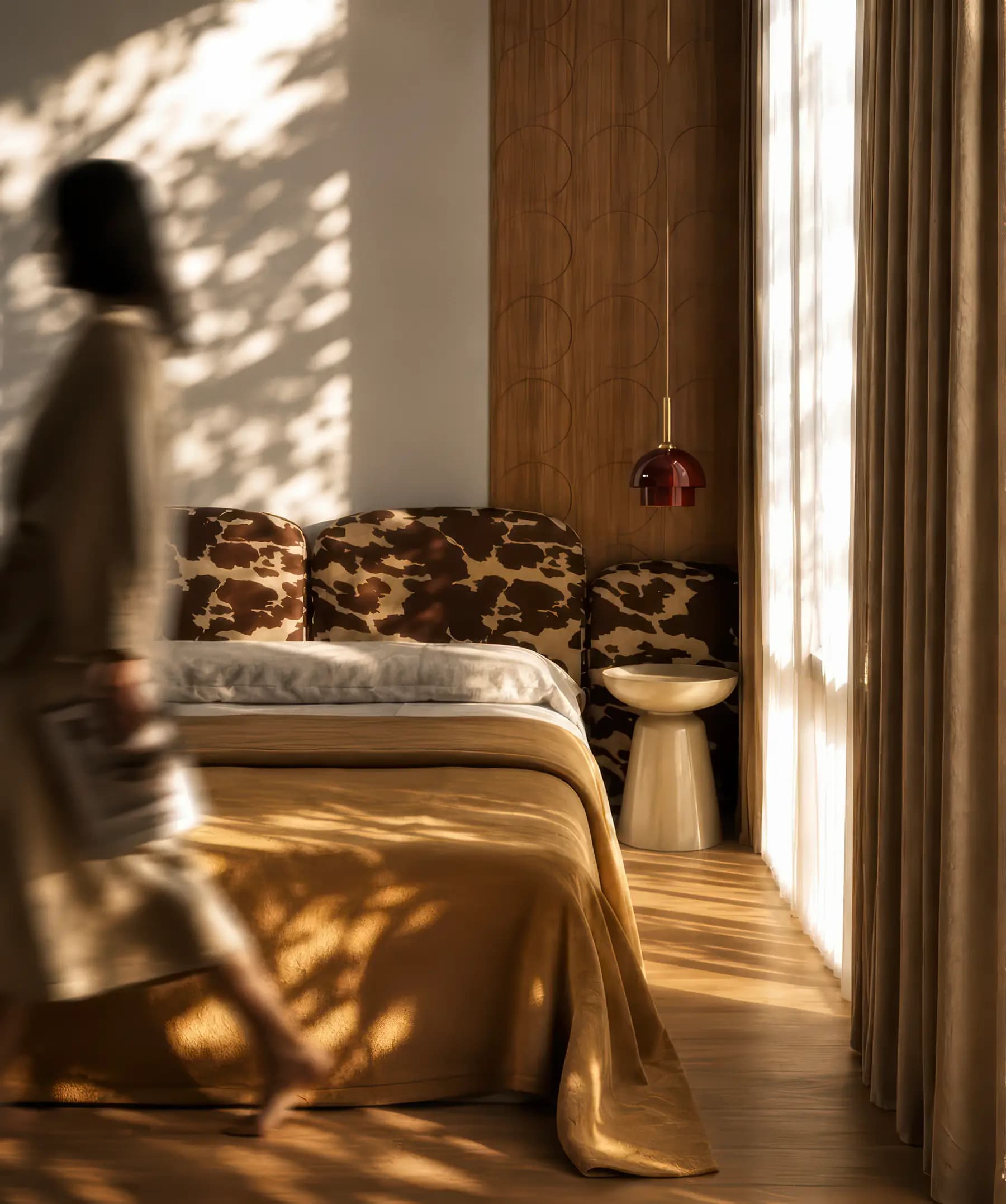 A woman walks through a bedroom bathed in filtered light